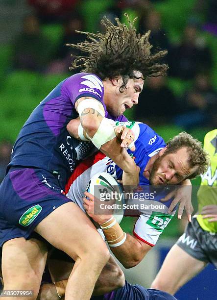 Clint Newton of the Newcastle Knights is tackled by Kevin Proctor of the Melbourne Storm during the round 24 NRL match between the Melbourne Storm...