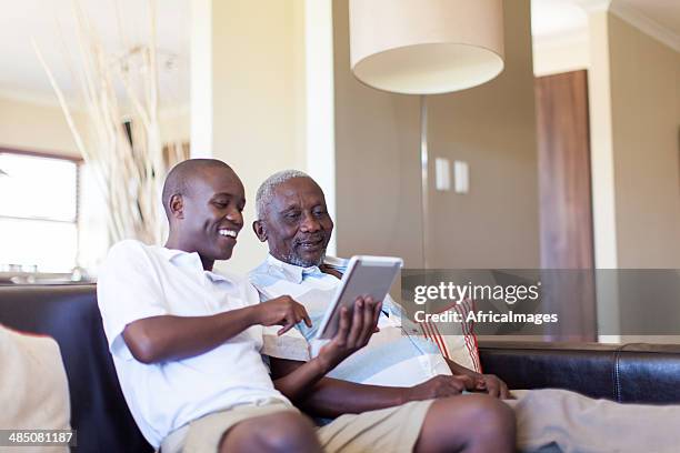 african grandson teaching his grandfather how to use a tablet - old point comfort stock pictures, royalty-free photos & images