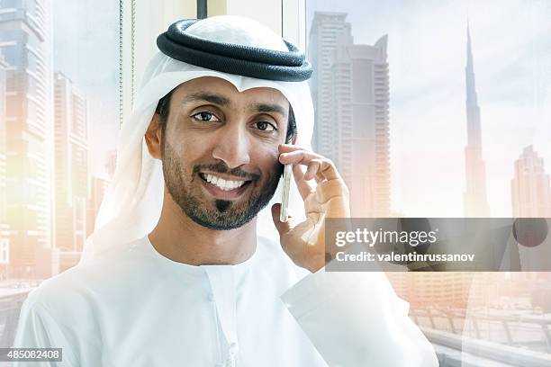 emirati smiling businessmen in dubai with mobile phone - emirati man portrait stockfoto's en -beelden