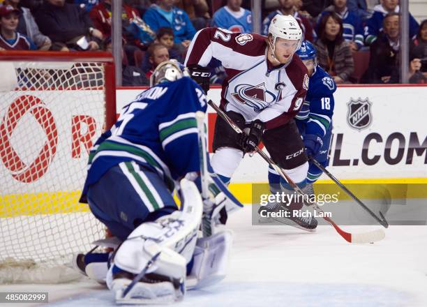 Gabriel Landeskog of the Colorado Avalanche looks to get a shot on goalie Jacob Markstrom of the Vancouver Canucks while being pressured by Ryan...