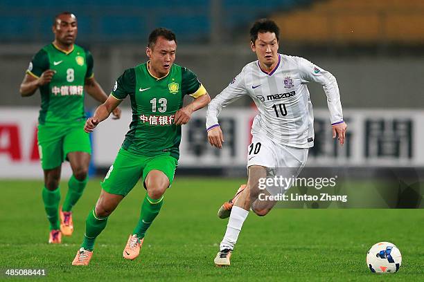 Yojiro Takahagi of Sanfrecce Hiroshima challenges Xu Yunlong of Beijing Guo'an during the AFC Champions match between Sanfrecce Hiroshima and Beijing...