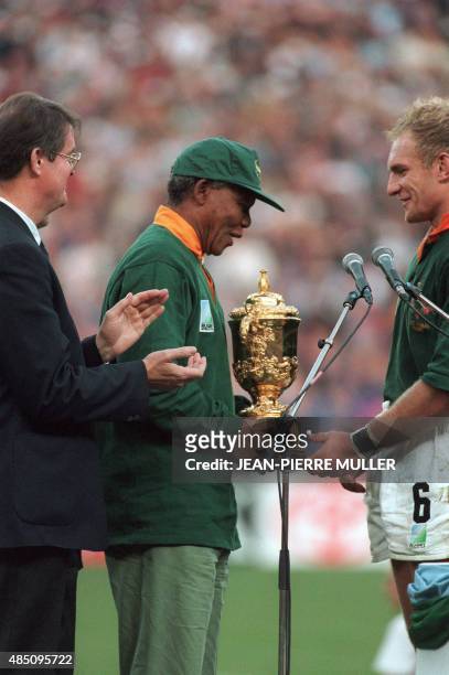 South African President Nelson Mandela congratulates Springbok skipper Francois Pienaar after handing him the William Webb Ellis trophy as Bernard...