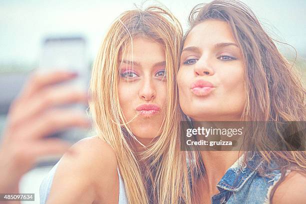 two cheerful hipster friends taking selfie photos on smart phone - pouting stock pictures, royalty-free photos & images