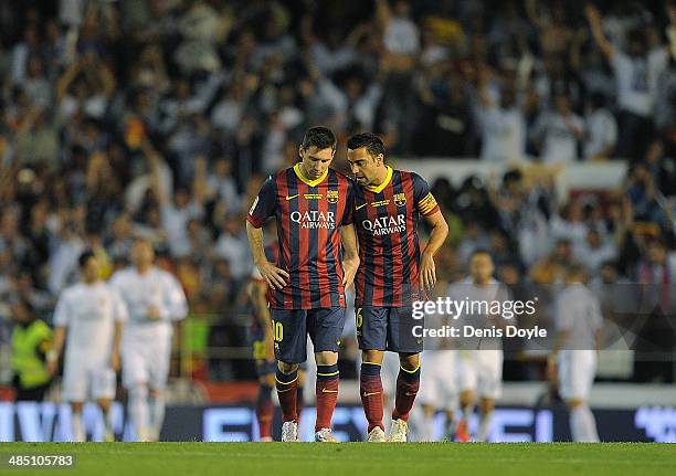 Lionel Messi and Xavi Hernandez of Barcelona react after Real Madrid scored their opening goal during the Copa del Rey Final between Real Madrid and...