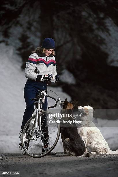 Sporting Look: Portrait of model Kathy Ireland feeding dogs aboard bicycle while wearing fleece pullover by Levi's Skiwear and pants by North Face...