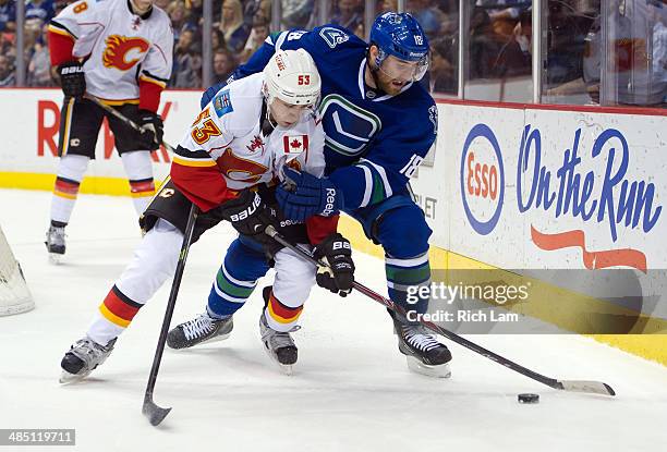 Johnny Gaudreau of the Calgary Flames battles with Ryan Stanton of the Vancouver Canucks for control of the puck during NHL action against the...