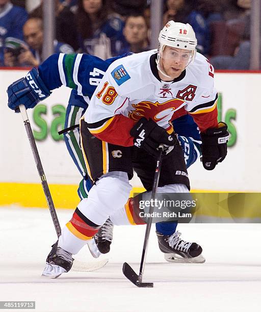 Matt Stajan of the Calgary Flames skates with the puck as Nicklas Jensen of the Vancouver Canucks gives chase during NHL action against the Vancouver...