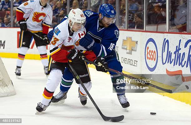 Johnny Gaudreau of the Calgary Flames and Ryan Stanton of the Vancouver Canucks battle for the puck during NHL action against the Vancouver Canucks...