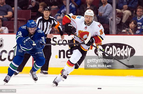 Galiardi of the Calgary Flames skates with the puck while being checked by Nicklas Jensen of the Vancouver Canucks during NHL action against the...