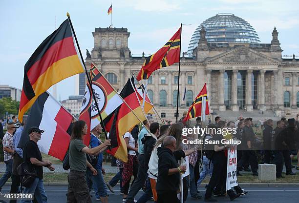 Supporters of the Pegida movement carry flags as they march past the Reichstag on August 24, 2015 in Berlin, Germany. Pegida is critical of Islam and...
