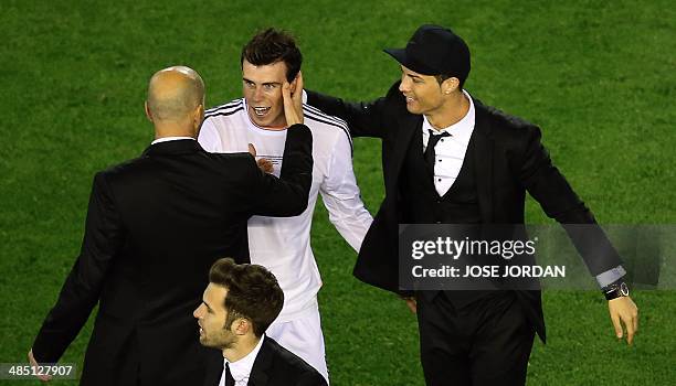 Real Madrid's assistant manager Zinedine Zidane congratulates Real Madrid's Welsh forward Gareth Bale and Real Madrid's Portuguese forward Cristiano...