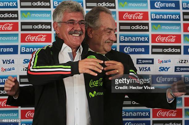 Decio de Maria president of FEMEXFUT helps Ricardo Ferretti head coach of Mexico to wear a Mexico's national team jacket during a press conference to...