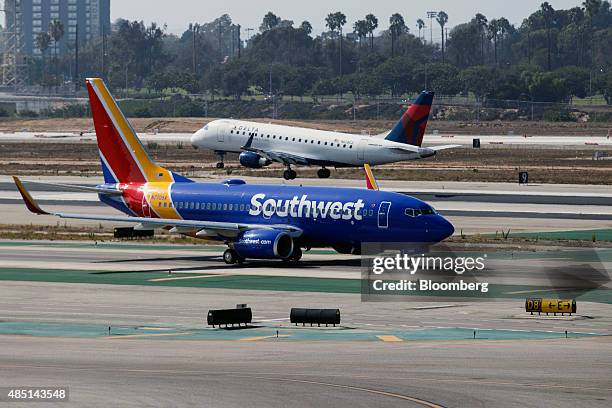 Southwest Airlines Boeing Co. 737-700 jet taxis to Terminal 1 as a Delta Air Lines Inc. Embraer SA 175 plane lands at Los Angeles International...