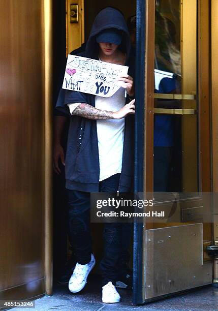 Singer Justin Bieber steps out of the Z100 building with a sign covering his face on August 24, 2015 in New York City.