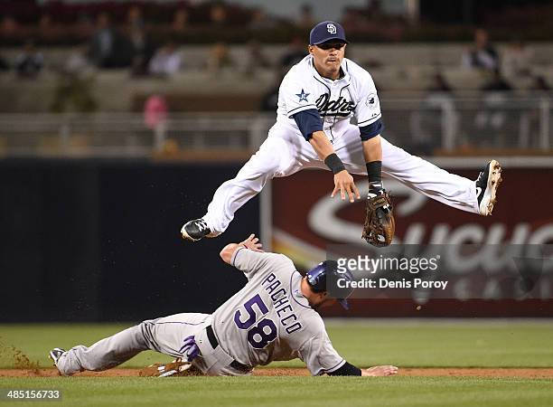 Everth Cabrera of the San Diego Padres jumps over Jordan Pacheco of the Colorado Rockies as he tries to turn a double play during the third inning of...