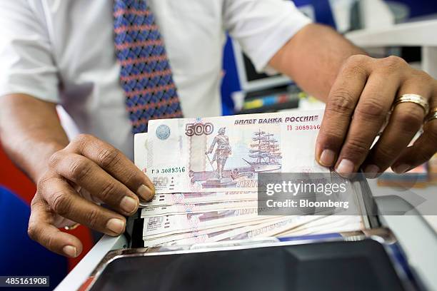 An employee uses a counting machine to count five hundred Russian Ruble notes in this arranged photograph in London, U.K., on Monday, Aug. 24, 2015....