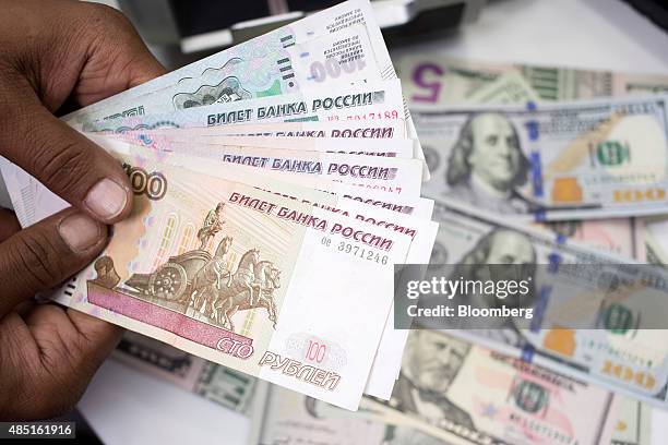 An employee holds Russian Ruble notes over a pile of American Dollar bills in this arranged photograph in London, U.K., on Monday, Aug. 24, 2015. The...