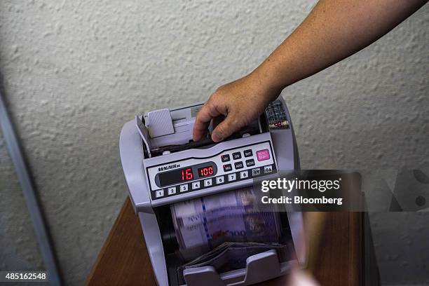An employee counts Malaysian one-hundred ringgit banknotes using a money-counting machine at a currency exchange store at Bukit Bintang in Kuala...