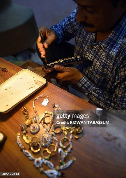 Pakistani jeweller prepares pieces for a necklace at his gold workshop in Karachi on August 25, 2015. Prices of crude oil and most other commodities...