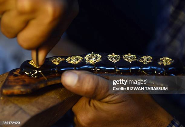 Pakistani jeweller prepares pieces for a necklace at his gold workshop in Karachi on August 25, 2015. Prices of crude oil and most other commodities...