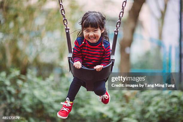 little girl swinging on the swing joyfully - pony play stock-fotos und bilder