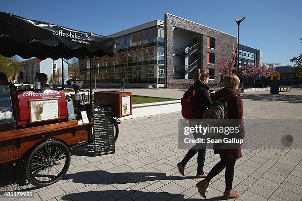 Students walk with coffee they bought from an outdoor stand on the campus of the European University Viadrina on April 16, 2014 in Frankfurt an der...