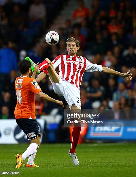 Peter Crouch of Stoke City challenges for the ball with Jonathan Smith of Luton Town during the Capital One Cup second round match between Luton Town...