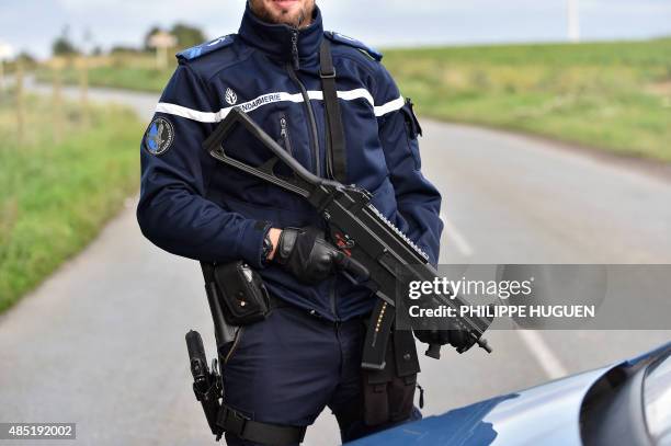 Gendarme holds a HK UMP submachine gun as he blocks a road near a travelers camp, the site of a shooting which killed four people and seriously...