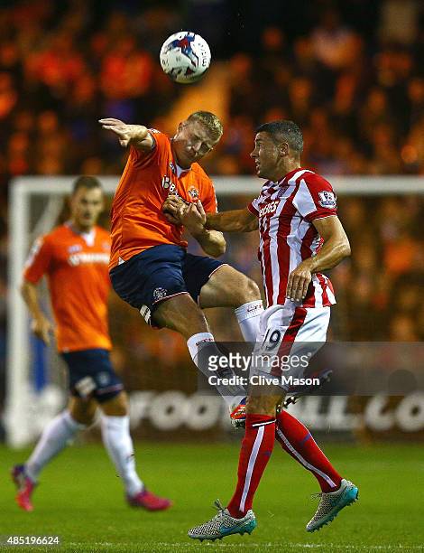 Scott Griffiths of Luton Town wins a header with Jonathan Walters of Stoke City during the Capital One Cup second round match between Luton Town and...