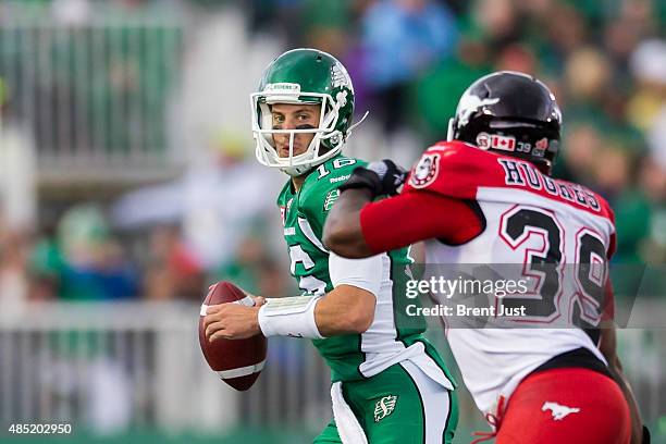Brett Smith of the Saskatchewan Roughriders looks to avoid the rush of Charleston Hughes of the Calgary Stampeders in a game between the Calgary...