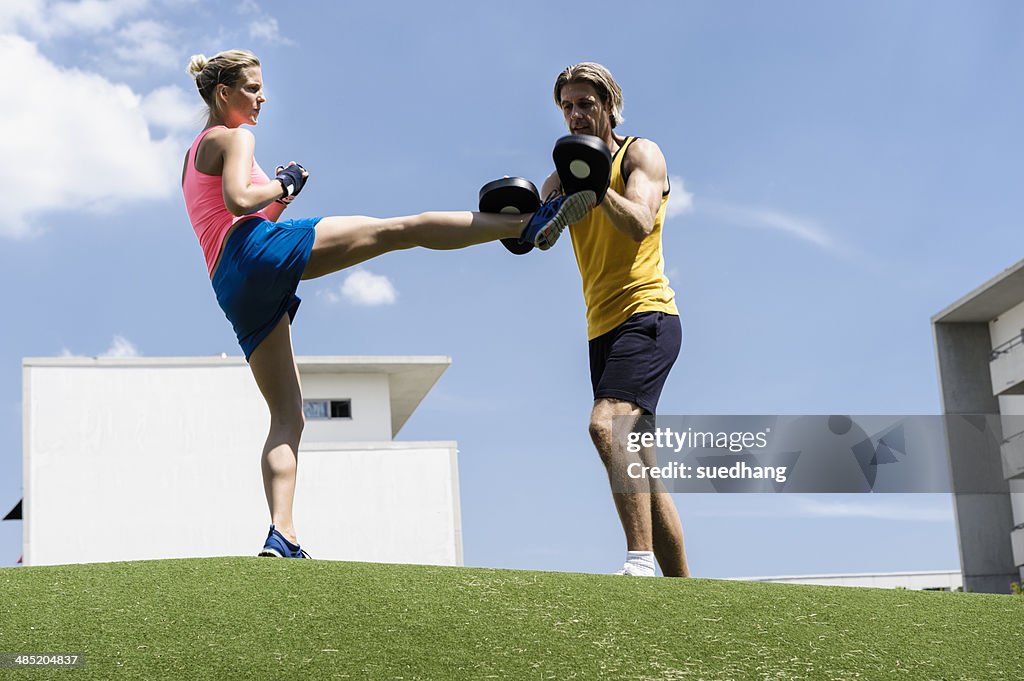 Female kick boxer and personal trainer in park