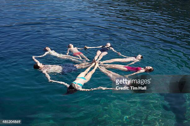 family group of eight floating on sea in a circle - synchronized swimming stock-fotos und bilder