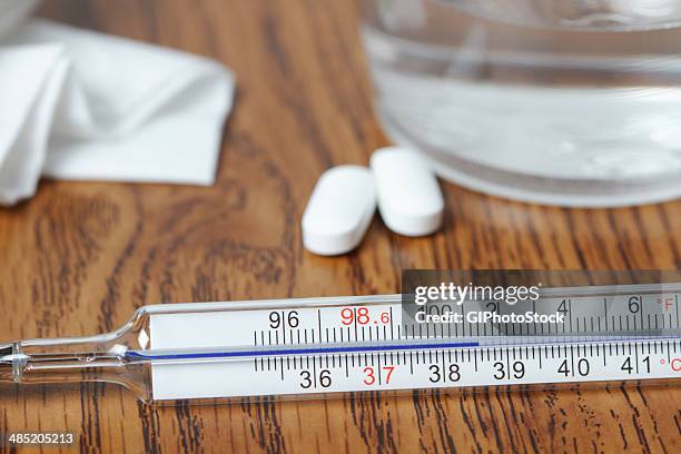 galinstan thermometer showing elevated body temperature from fever, paracetamol pills, glass of water, tissue - virus grippe stock pictures, royalty-free photos & images