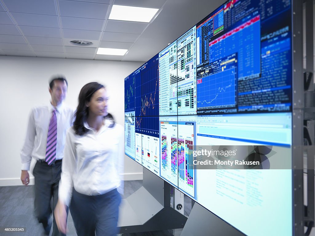 Financial analysts looking at screens in control room