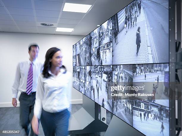 security workers walking past cctv screens in control room - south ruislip stock pictures, royalty-free photos & images