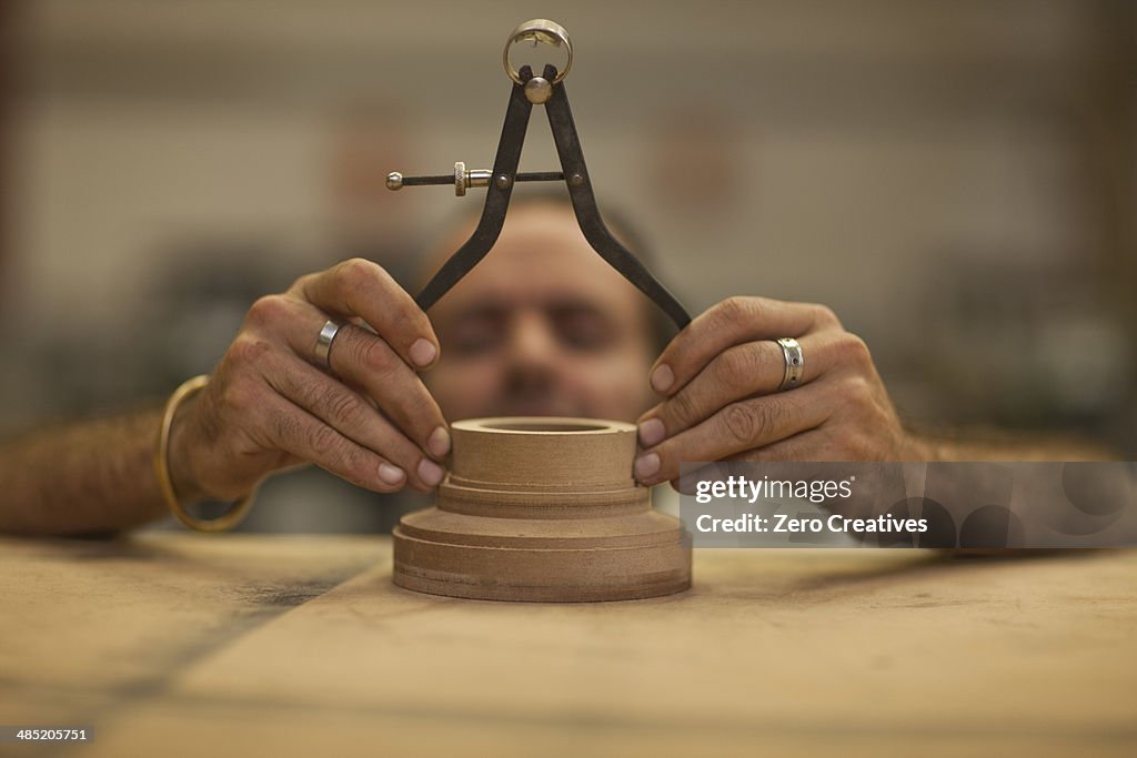 Close up of carpenter measuring turning wood in workshop