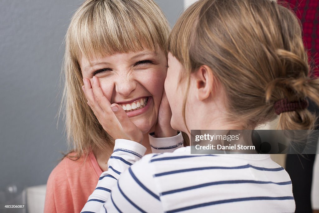 Girl cupping young woman's face