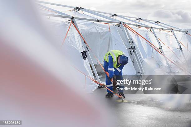 emergency response team worker adjusting tent anchor - heysham stock pictures, royalty-free photos & images