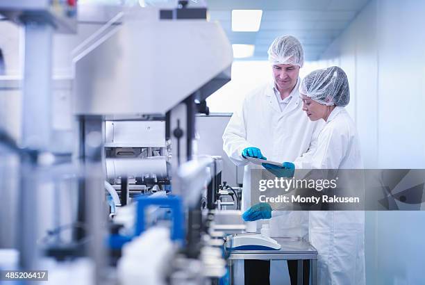 workers inspecting product in pharmaceutical factory - fábrica farmacéutica fotografías e imágenes de stock