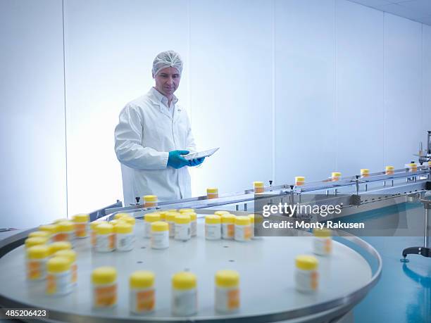 worker inspecting packaging in pharmaceutical factory - fábrica farmacéutica fotografías e imágenes de stock