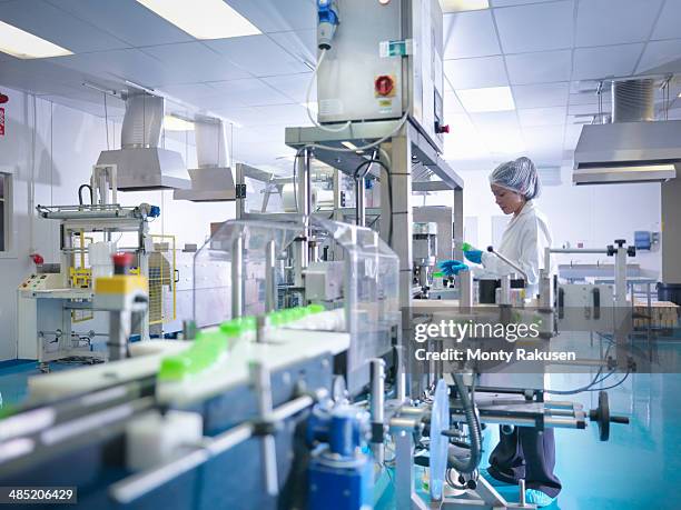 worker inspecting products on production line in pharmaceutical factory - farmaceutische-fabriek stockfoto's en -beelden