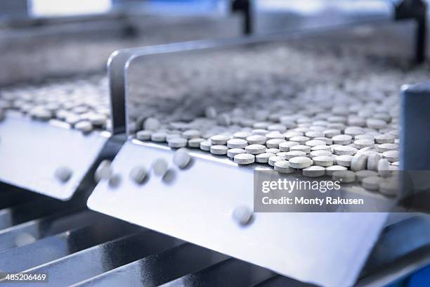 close up of tablets in packing machine in pharmaceutical factory - farmaceutische-fabriek stockfoto's en -beelden