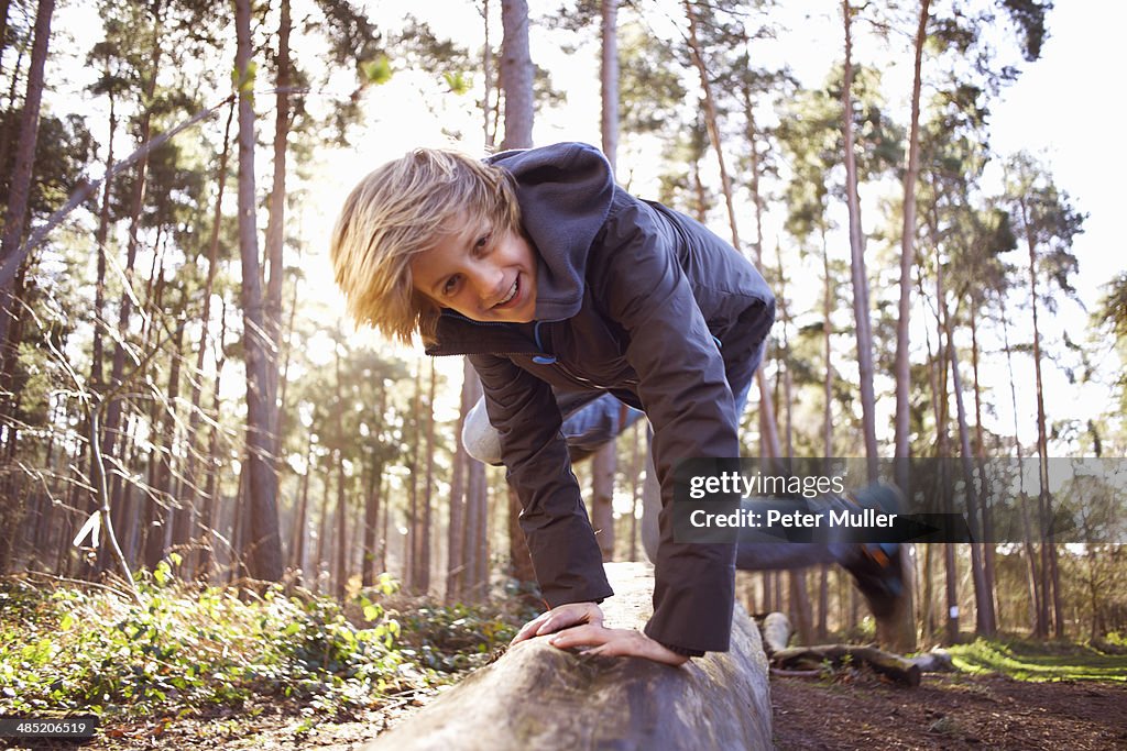 Boy jumping over a tree trunk in forest