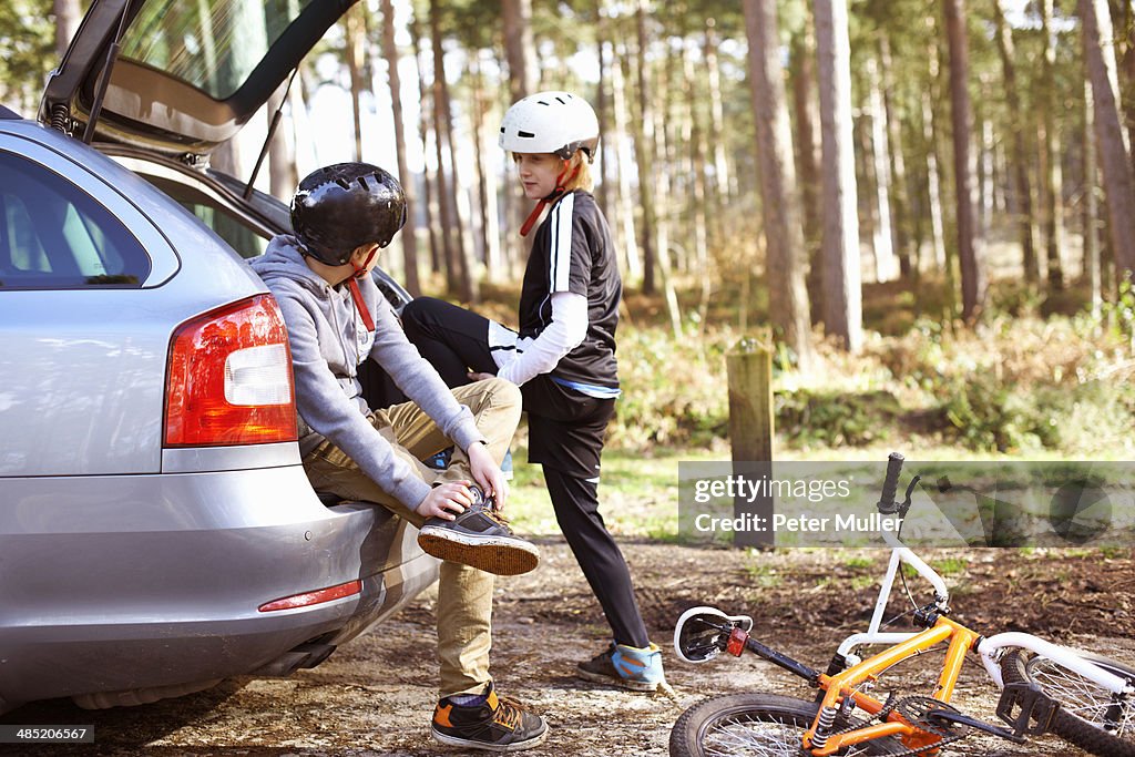 Twin brothers preparing to ride BMX bikes in forest