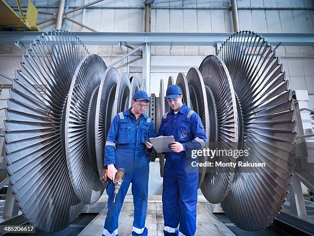 engineers discussing notes in front of steam turbine in workshop - hydroelectric power stock pictures, royalty-free photos & images
