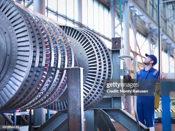 engineer lifting high pressure steam turbine with crane in workshop - wasserkraft stock-fotos und bilder