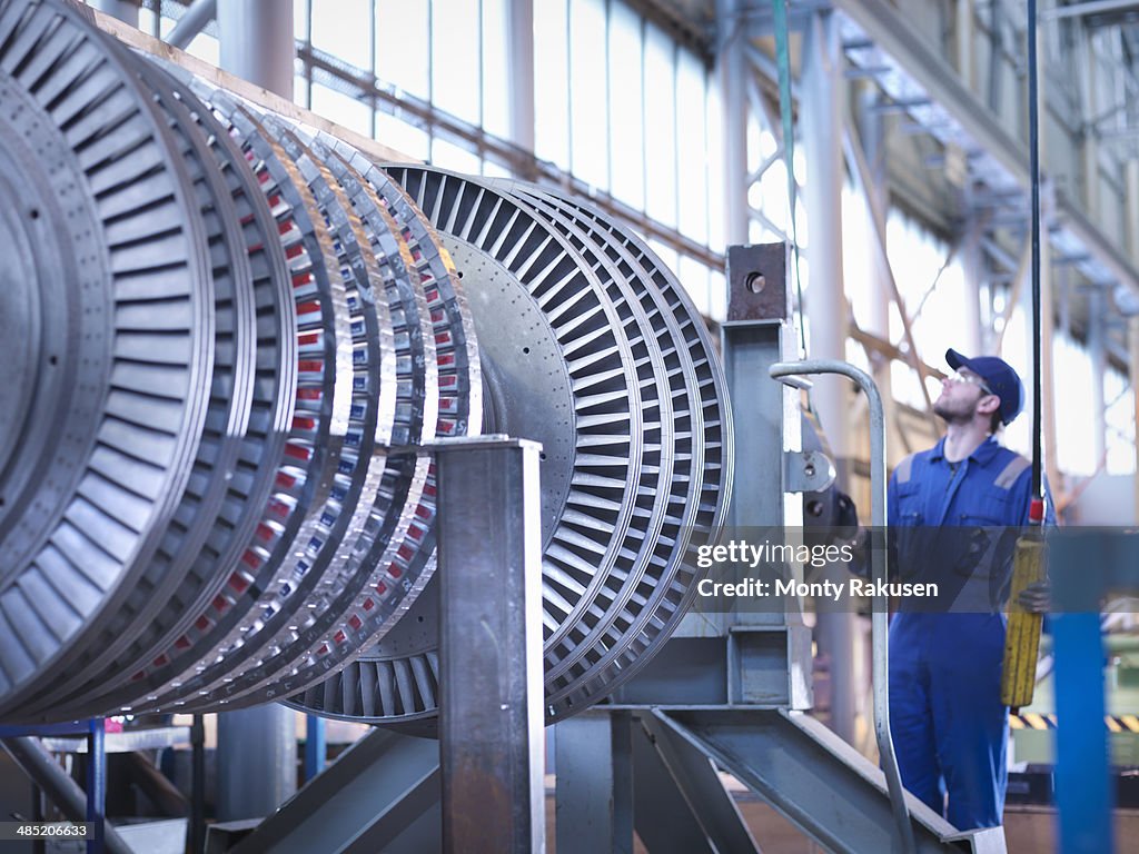 Engineer lifting high pressure steam turbine with crane in workshop