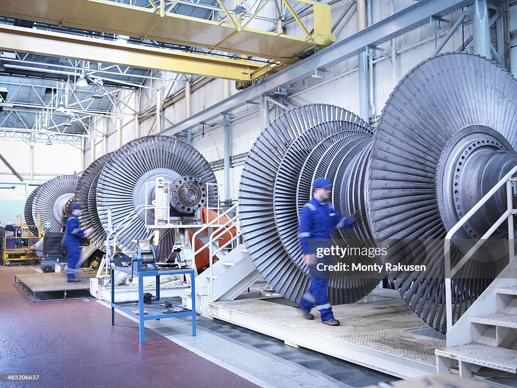 Engineers with low pressure steam turbines in repair bays in workshop