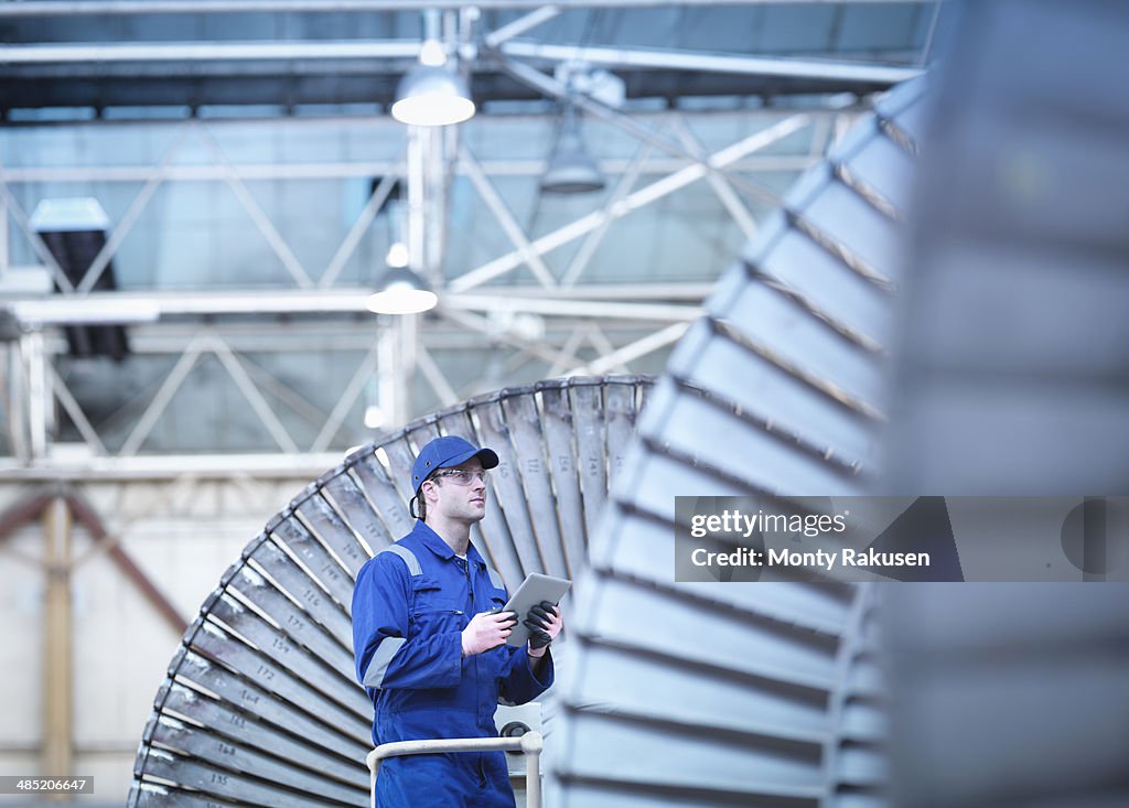 Engineer inspecting steam turbine in repair bay