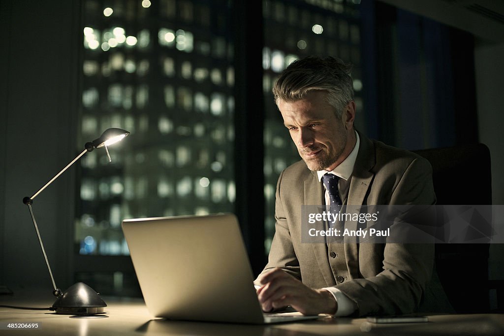 Businessman working late in office on laptop